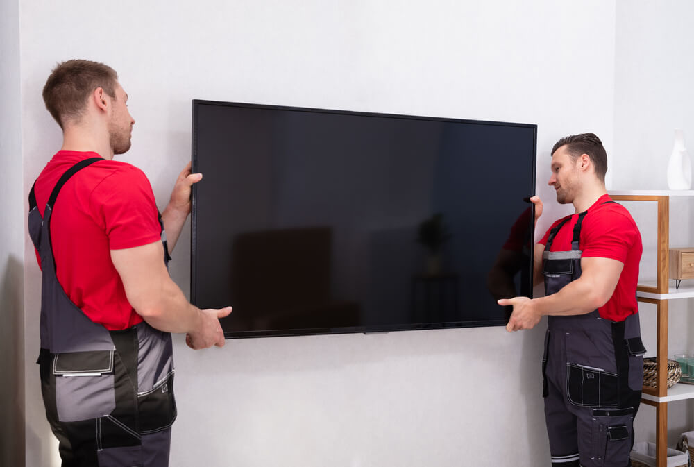 2 men hanging a tv with professional packing services