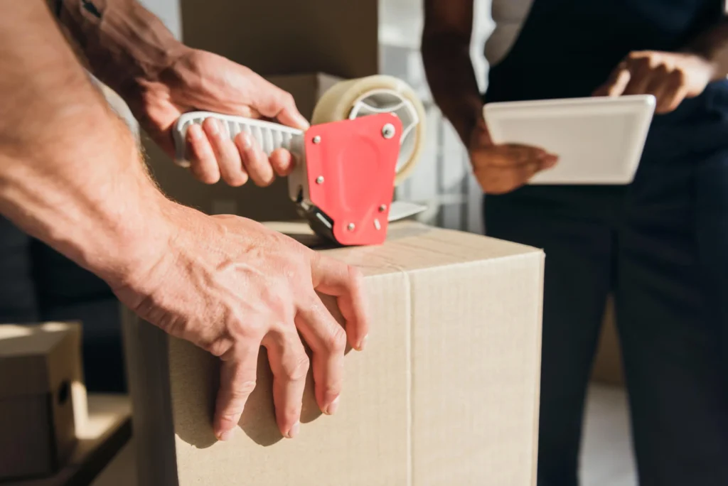 Worker sealing a moving box with packing tape, movers in Ann Arbor, MI