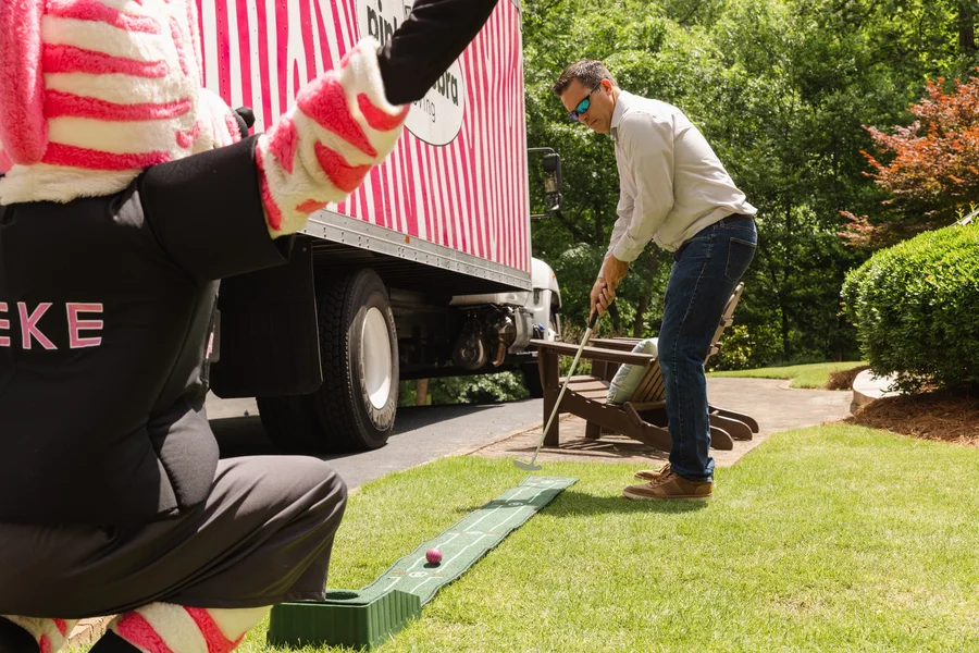 customer-playing-putting-game-with-pink-zebra-mascot-movers-montgomery