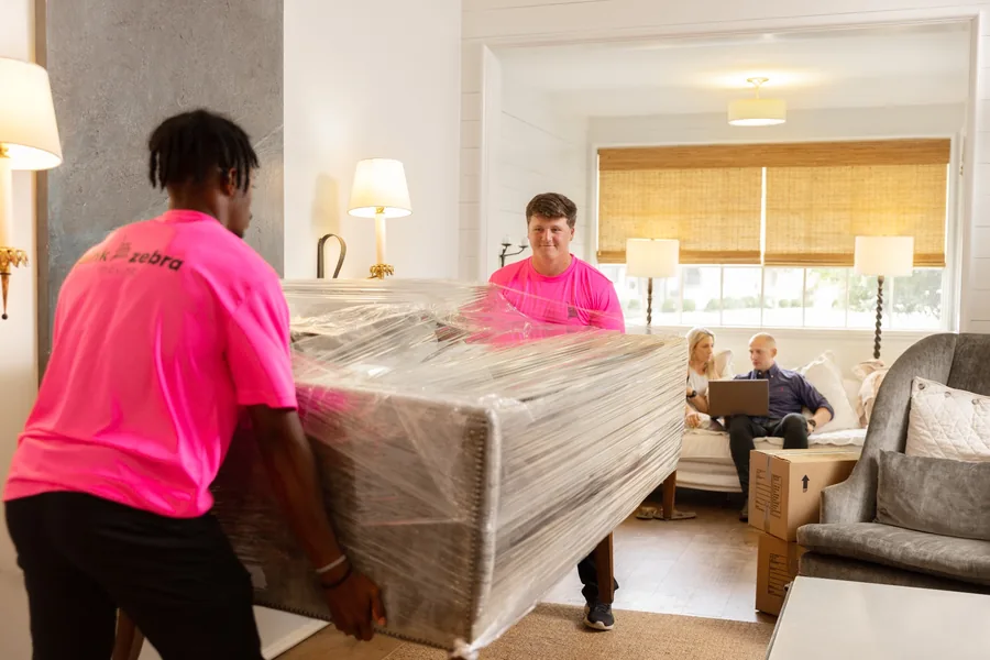 experienced movers carrying wrapped furniture into a home in oklahoma city ok