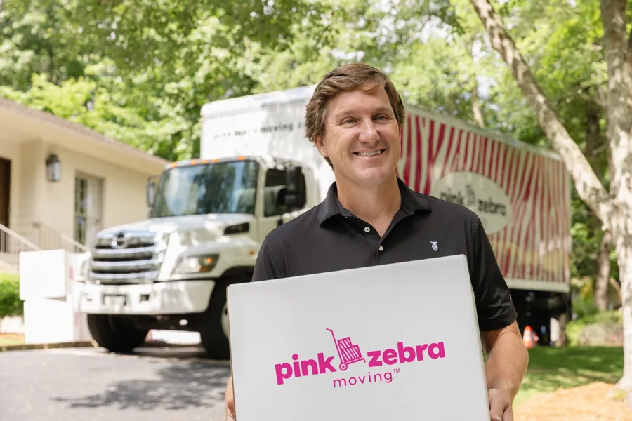 happy customer holding a moving box in front of a moving truck in round rock tx